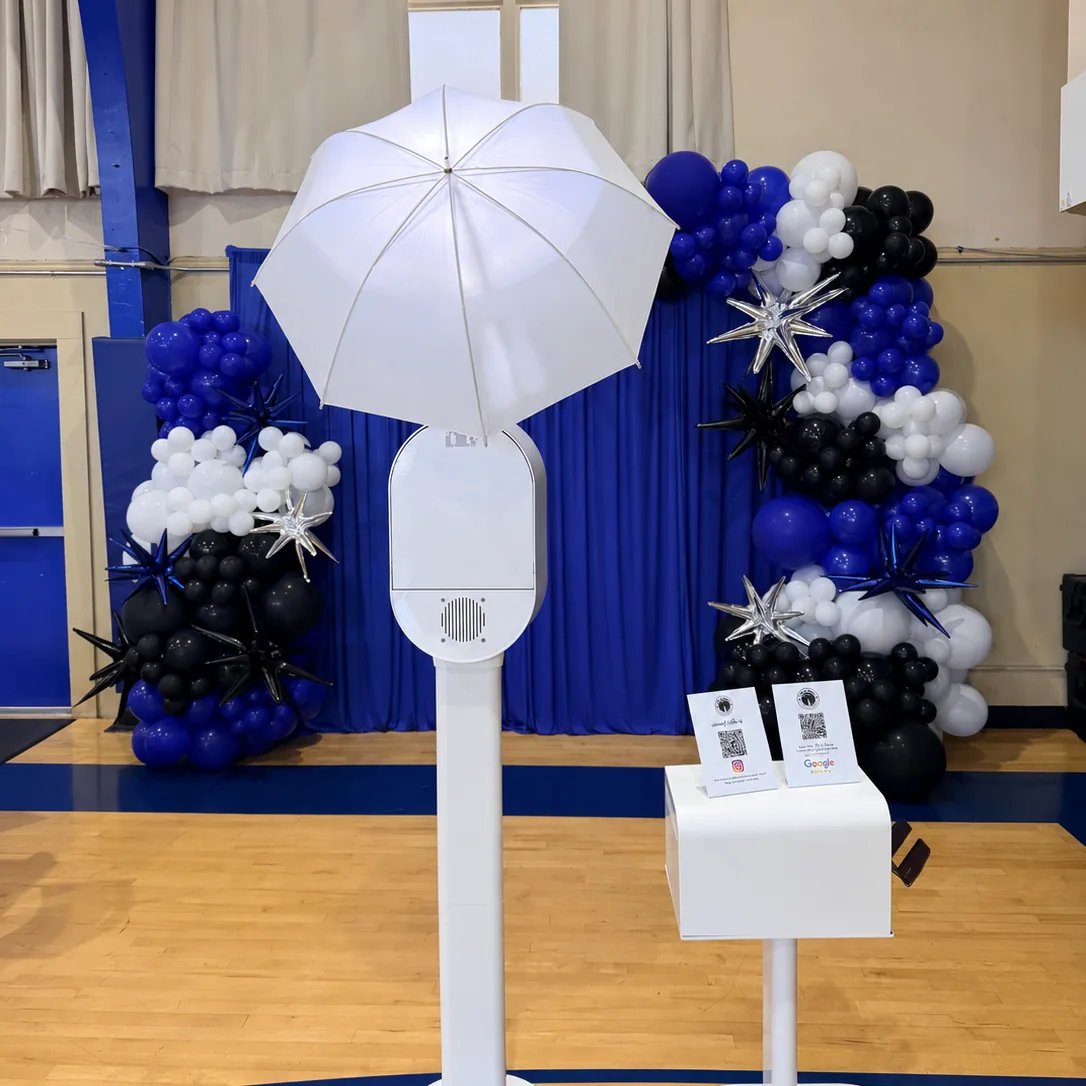 Photo booth with a blue, white and black balloon arch at a school event